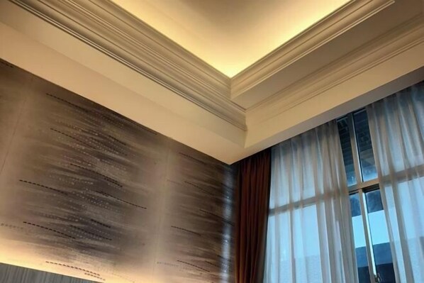 A room with a wooden wall panel, a large window with curtains, and a ceiling with recessed lighting. - Pacific Inn, Semporna (Semporna)