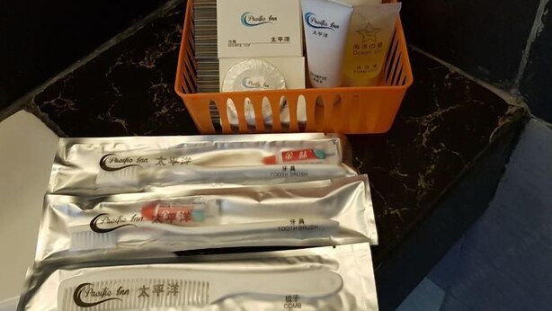 Un cesto con artículos de tocador y un juego de cepillos de dientes, con empaques de Pacific Inn.