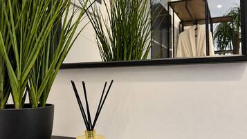 A modern interior with a potted plant, a decorative bottle, and a remote control on a dark surface.