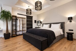 A modern bedroom with a large bed, a built-in wardrobe, a potted plant, and a ceiling light fixture.