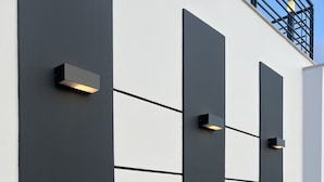 Fachada de edificio moderno con paneles negros grandes e iluminación empotrada.