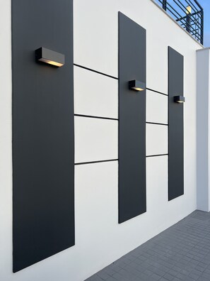 A modern building facade with large black panels and recessed lighting.
