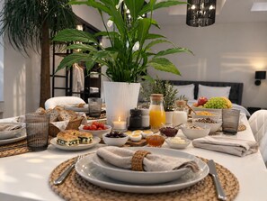 A breakfast setting with a variety of foods and drinks, including bread, fruits, and a candle. - Apollonio Suites (Corinth)