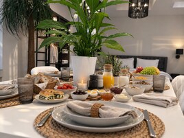 A breakfast setting with a variety of foods and drinks, including bread, fruits, and a candle.