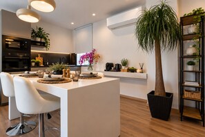 A modern kitchen with a central island, white chairs, and a dining table set for four.