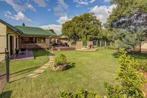 Un patio trasero bien cuidado con una terraza, una zona de barbacoa y un sendero de piedra que lleva a la casa.