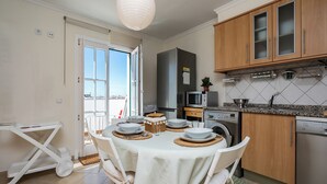 A modern kitchen with a dining area, including a table set for four, a microwave, a washing machine, and wooden cabinets.