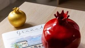 A brochure with a pomegranate and a golden ornament on a wooden surface. - Luxury Suite Tico San Diego (Granada)