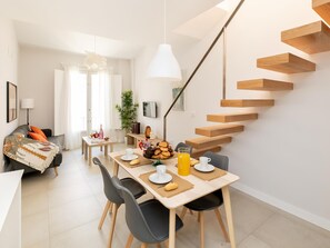 Een moderne leefruimte met een eethoek, een trap en een bank.