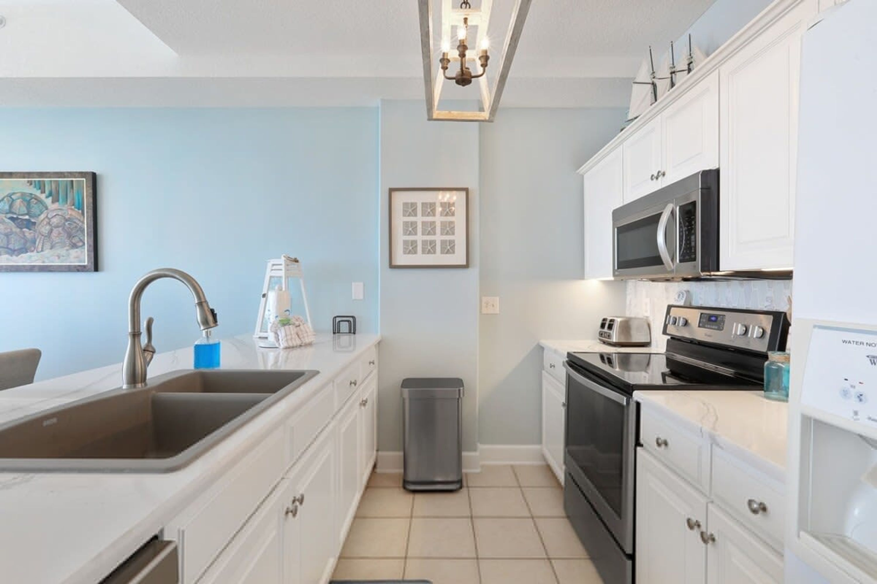A modern kitchen with white cabinets, stainless steel appliances, and a tiled backsplash.