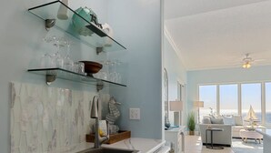 Une cuisine moderne avec une étagère en verre où sont posés des verres à vin et un meuble blanc.