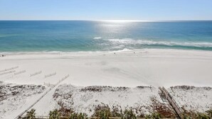 Une plage offrant une vue dégagée sur l’océan, avec un rivage sablonneux et quelques personnes qui s’y promènent.