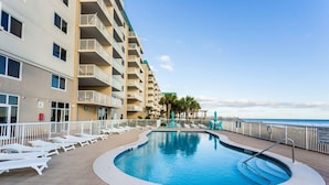 A pool area with lounge chairs and a building with balconies. - Sandy Key 635 2 BD 2BH 6th Floor (Pensacola)
