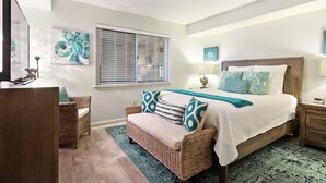 A bedroom with a large bed, a wicker sofa, a desk, and artwork on the walls. - Sandy Key 635 2 BD 2BH 6th Floor (Pensacola)