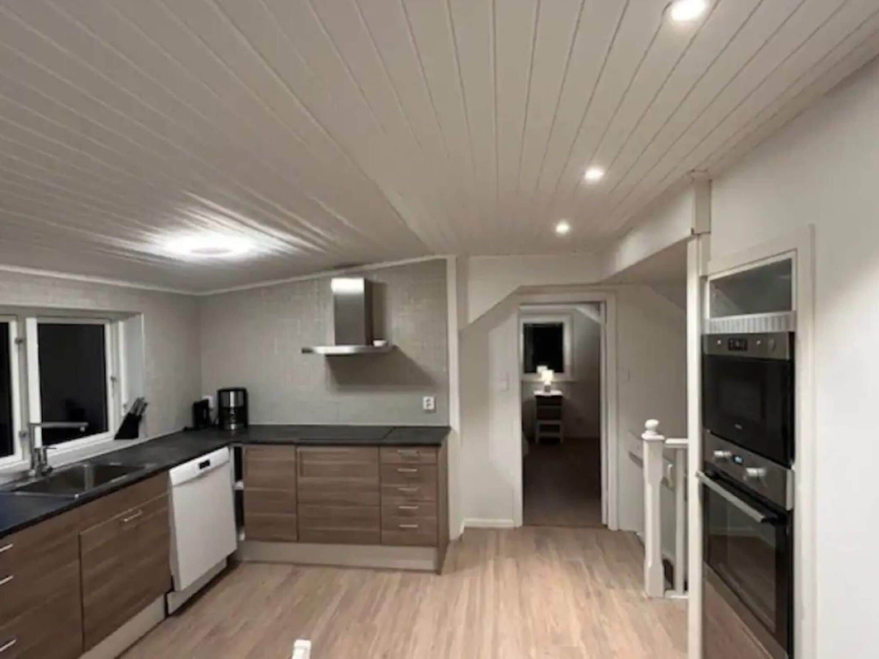 A modern kitchen with wooden cabinets, a dishwasher, and built-in ovens.