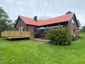 A two-story house with a red-tiled roof, a wooden deck, and a small patio area. - 5 Star Holiday Home in Mollosund (Mollösund)