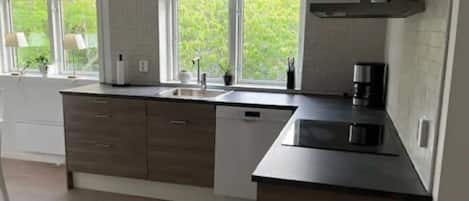 A modern kitchen with a large island, built-in appliances, and a view of greenery outside.