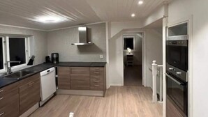 A modern kitchen with wooden cabinets, a dishwasher, a stove, and a microwave. - 5 Star Holiday Home in Mollosund (Mollösund)
