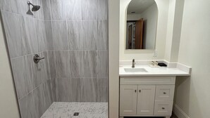 Un baño con ducha, tocador y espejo.