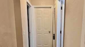 A hallway with a white door at the end, a light switch on the wall, and a vent on the right. - Adventure Coast 4/2, Big Yard (Spring Hill)
