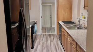 A kitchen with wooden cabinets, a black refrigerator, a sink, and a door leading to another room. - Adventure Coast 4/2, Big Yard (Spring Hill)