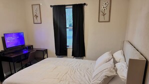 A hotel room with a bed, a desk with a computer, and a window with black curtains. - Adventure Coast 4/2, Big Yard (Spring Hill)