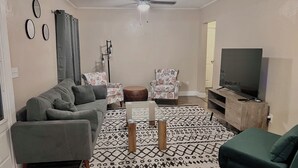 A living room with a sofa, two patterned armchairs, a coffee table, a TV, and a ceiling fan. - Adventure Coast 4/2, Big Yard (Spring Hill)