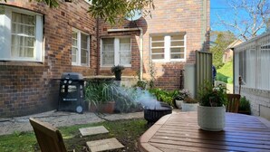 Une maison en briques avec un patio, un barbecue et un jardin.