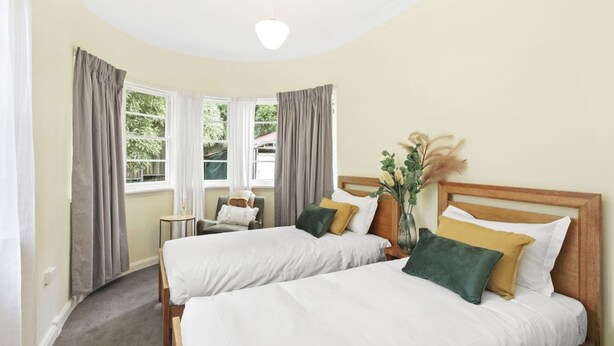 Une chambre d’hôtel avec deux lits, une petite table et une fenêtre avec des rideaux.