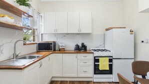 A compact kitchen with white cabinets, a microwave, a gas stove, and a sink. - Katoomba Getaway 3 bedrooms (Katoomba)