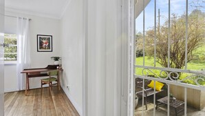 A balcony with a wooden desk, chair, and a yellow pillow. - Katoomba Getaway 3 bedrooms (Katoomba)