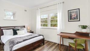 A bedroom with a wooden bed, a desk, and a chair. There is a window with curtains and a framed picture on the wall. - Katoomba Getaway 3 bedrooms (Katoomba)