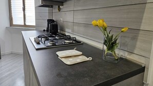A modern kitchen with a gas stove, a coffee maker, and a vase with tulips on the counter.