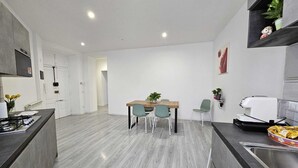 A modern kitchen with a dining area, featuring a built-in stove, a sink, and a dining table with chairs.