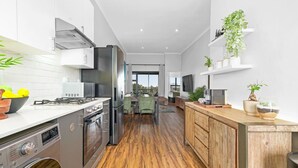 A modern kitchen with stainless steel appliances, wooden cabinets, and a dining area with a view.