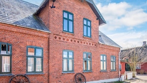 A red brick building with multiple windows and a large wheel on the ground. - Captain House BnB in Fano (Fano)