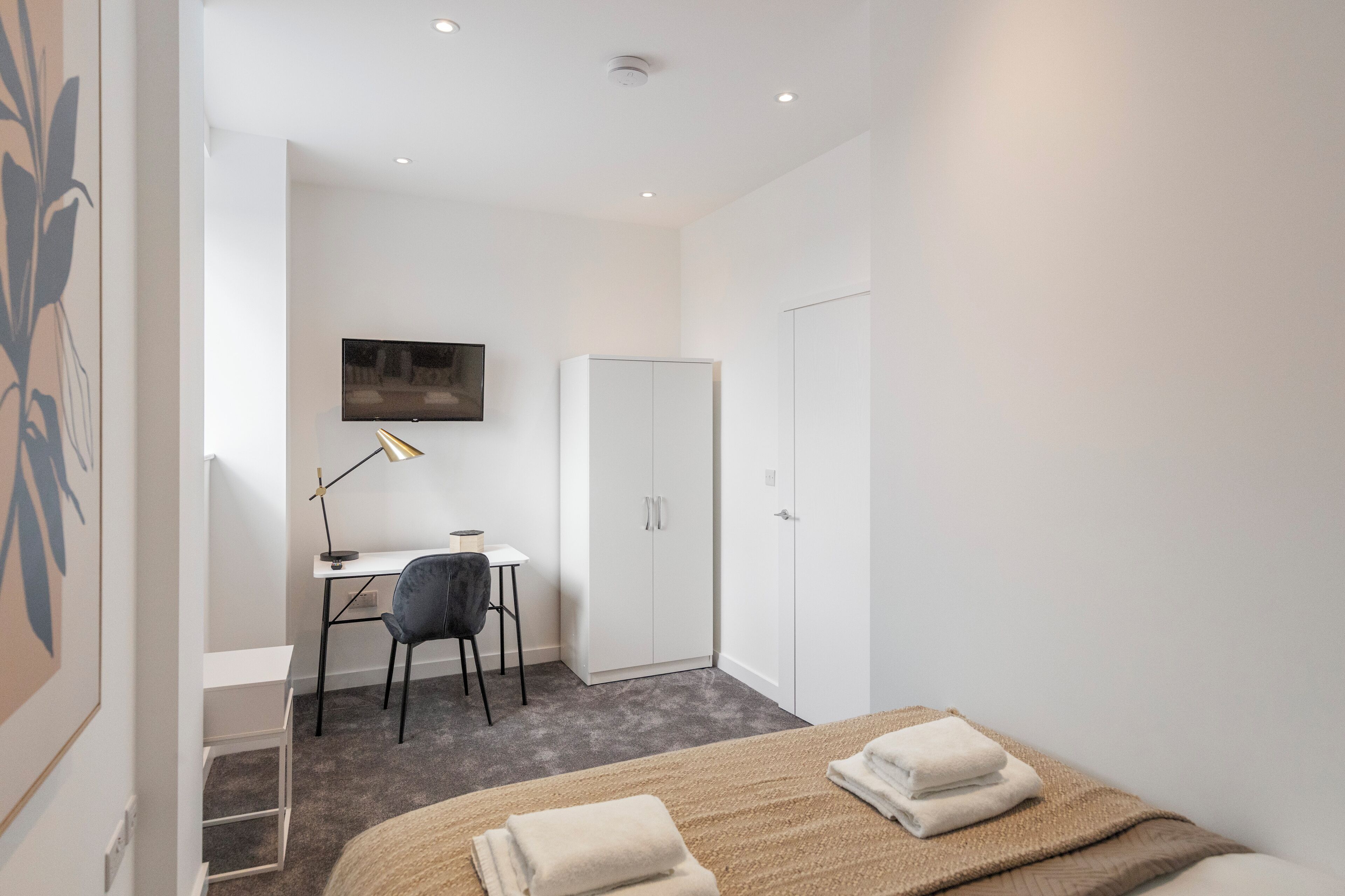 Ein modernes Schlafzimmer mit Bett, Schreibtisch, Stuhl und Kleiderschrank.