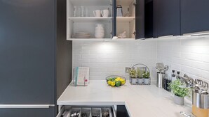 Una cocina moderna con armarios oscuros, encimeras blancas y una variedad de utensilios y utensilios de cocina.