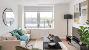 Una sala de estar moderna con sofá, mesa de centro y un ventanal con vistas a la ciudad.