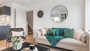 Una sala de estar moderna con un sofá, una mesa de centro, una silla, un reloj y un espejo.