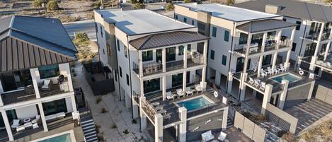 A modern multi-story residential building with a rooftop pool and outdoor seating areas.