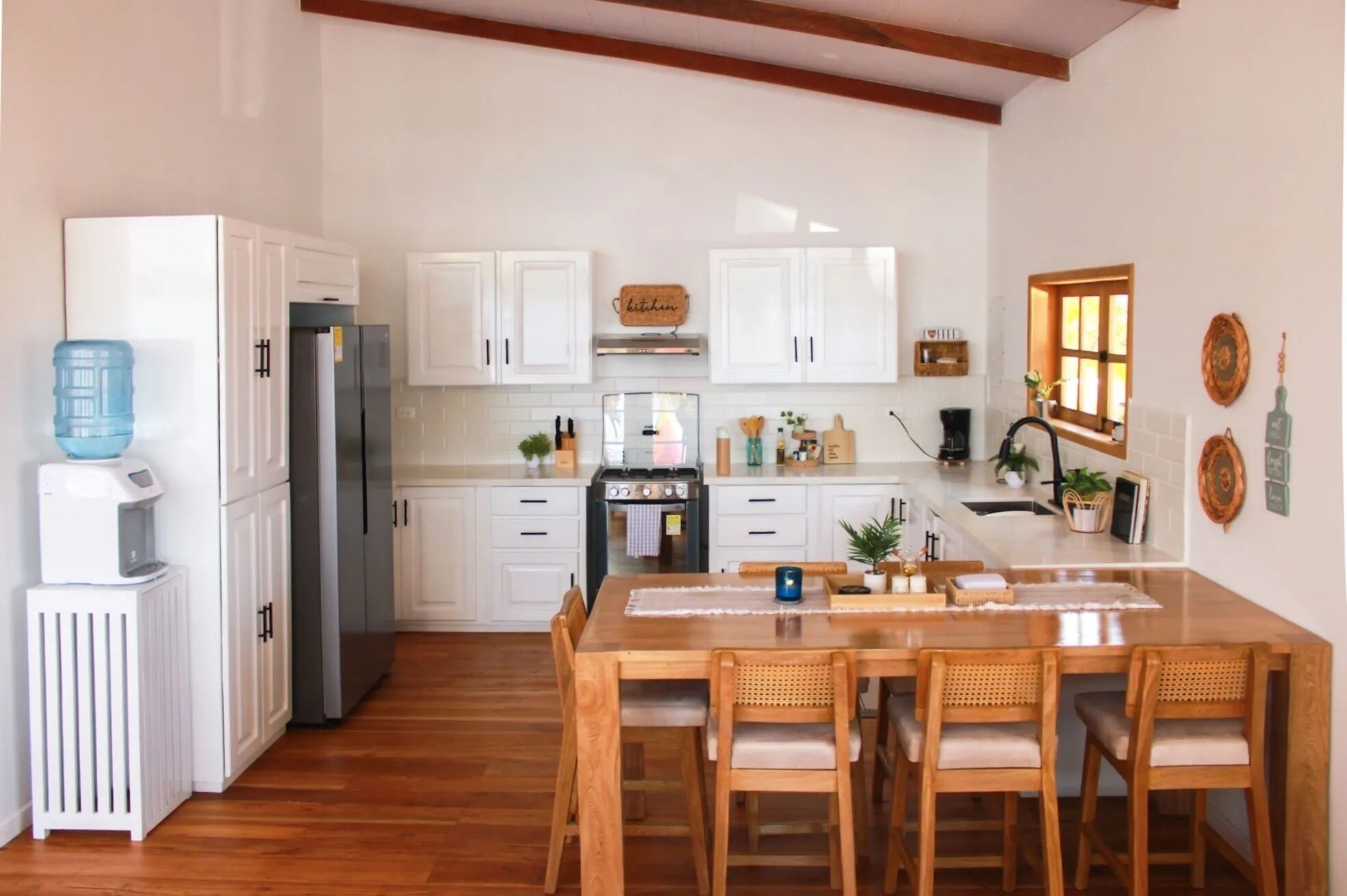 Una cocina moderna con armarios blancos, una isla central y sillas de madera.