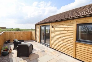 A wooden building with a tiled roof, a sliding glass door, and a patio area with outdoor furniture. - Moments From Beach/lodge/naturereserve/ Sandilands (Mablethorpe)