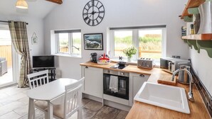 A compact kitchen with a dining area, a large window, and a clock on the wall. - Moments From Beach/lodge/naturereserve/ Sandilands (Mablethorpe)