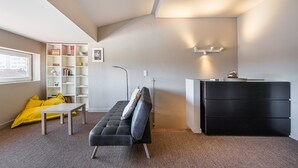 Una habitación moderna con sofá, escritorio, estantería y cómoda.
