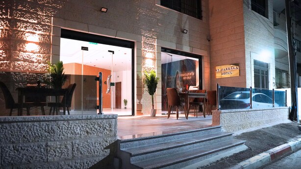 The exterior of St. Barbara Hotel with a stone facade, a glass entrance, and a signboard. - St Barbara Hotel (Bethlehem)