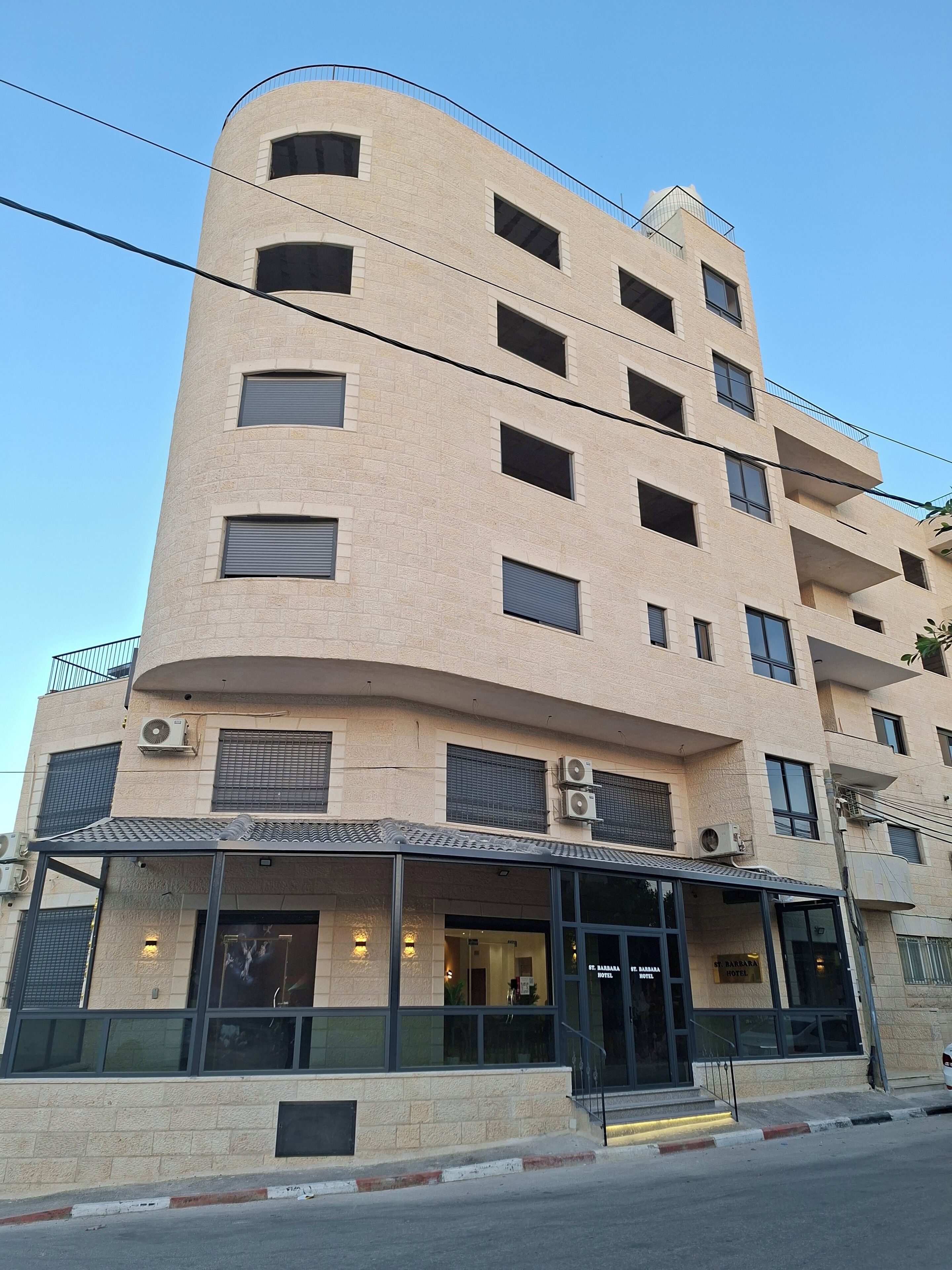 Ein mehrstöckiges Hotel mit beiger Fassade, Klimaanlagen und einem Eingangsbereich auf Erdgeschossniveau mit Überdachung.