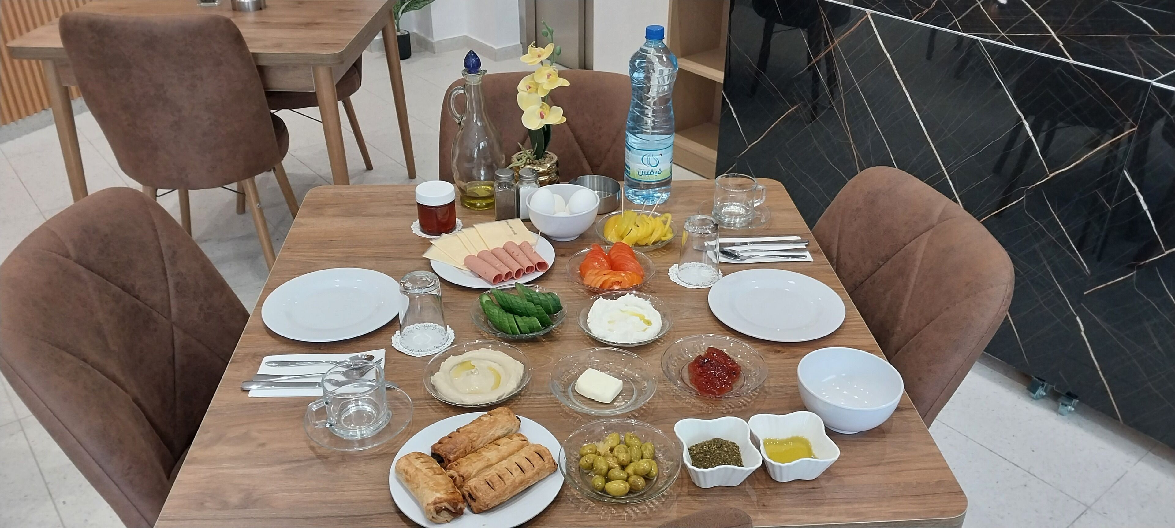 Una mesa de comedor dispuesta con diferentes platos, incluyendo panes, verduras y salsas.