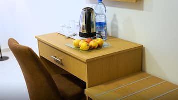 Ein Holztisch mit einem Glaseinsatz, der Früchte, eine Wasserflasche und einen Wasserkocher enthält.