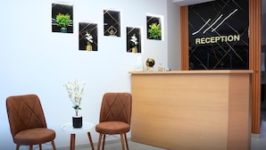 A reception area with a wooden desk, two brown chairs, and a small table with a plant. - St Barbara Hotel (Bethlehem)